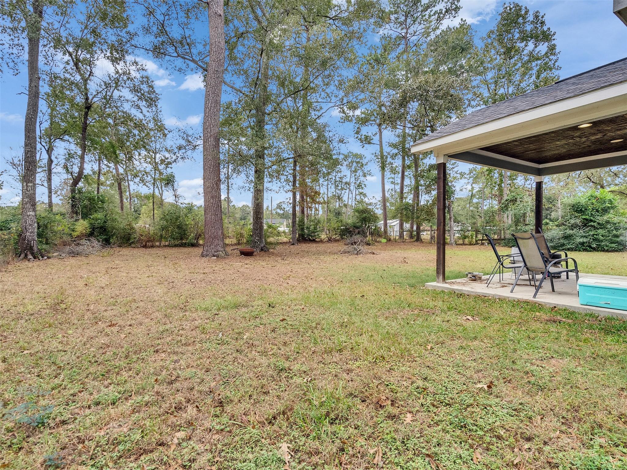 Backyard with mature trees and a covered patio with outdoor seating.