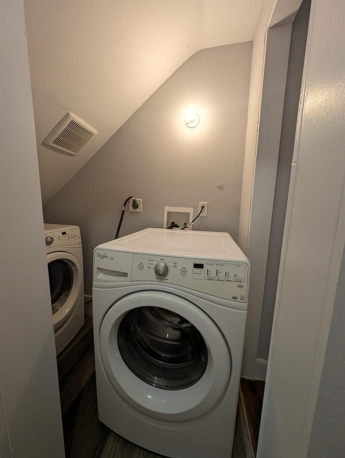 Laundry closet with a white front-loading washer and a second laundry machine beside it.