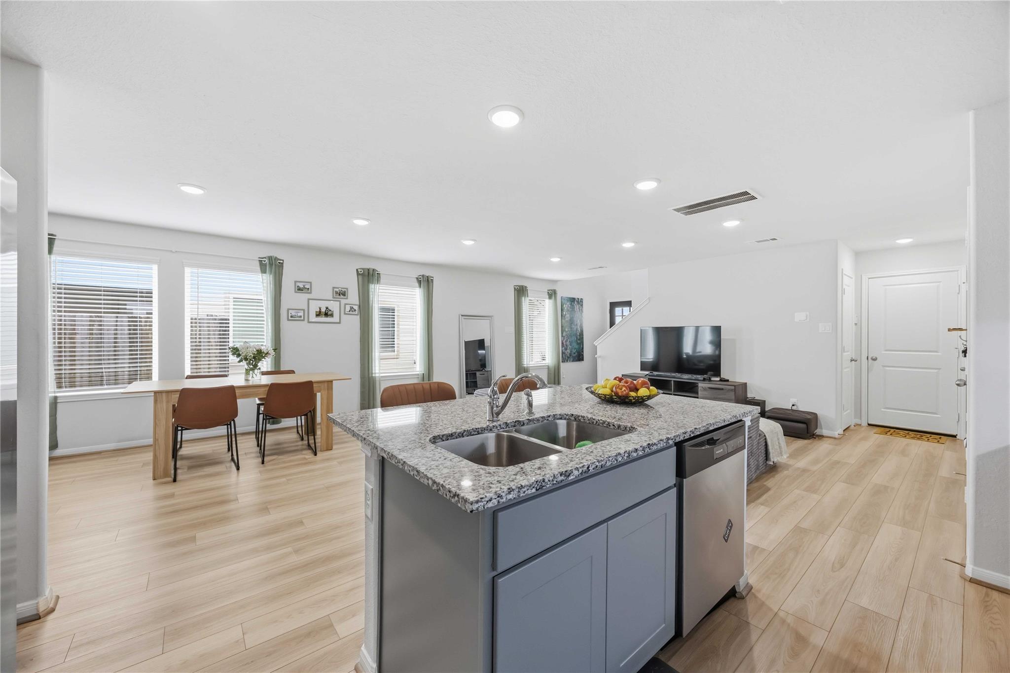 Open-plan kitchen with a granite island and double sink, dining table, and living area.