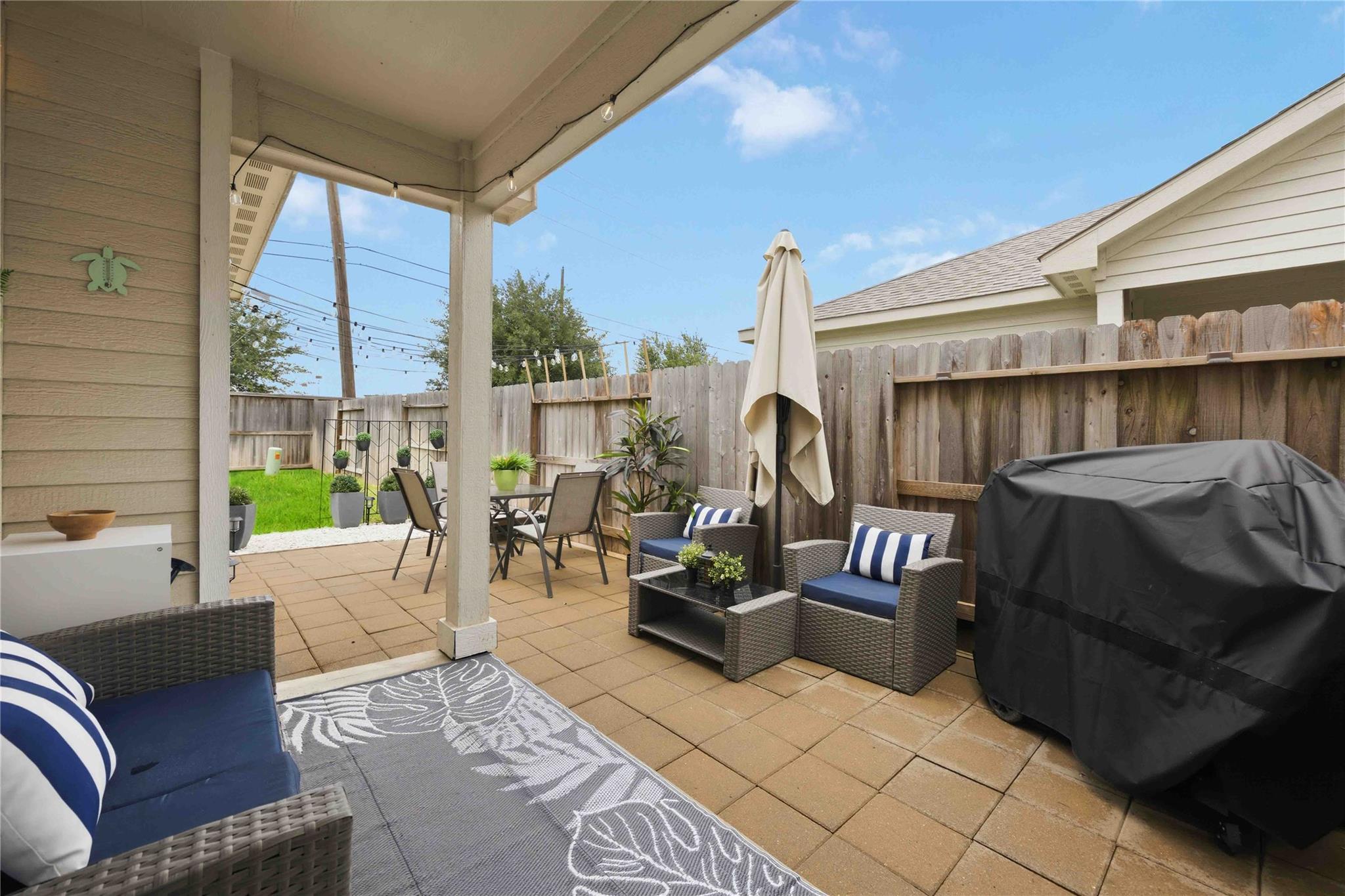 Covered patio with wicker lounge seating, a dining table, and a fenced backyard.
