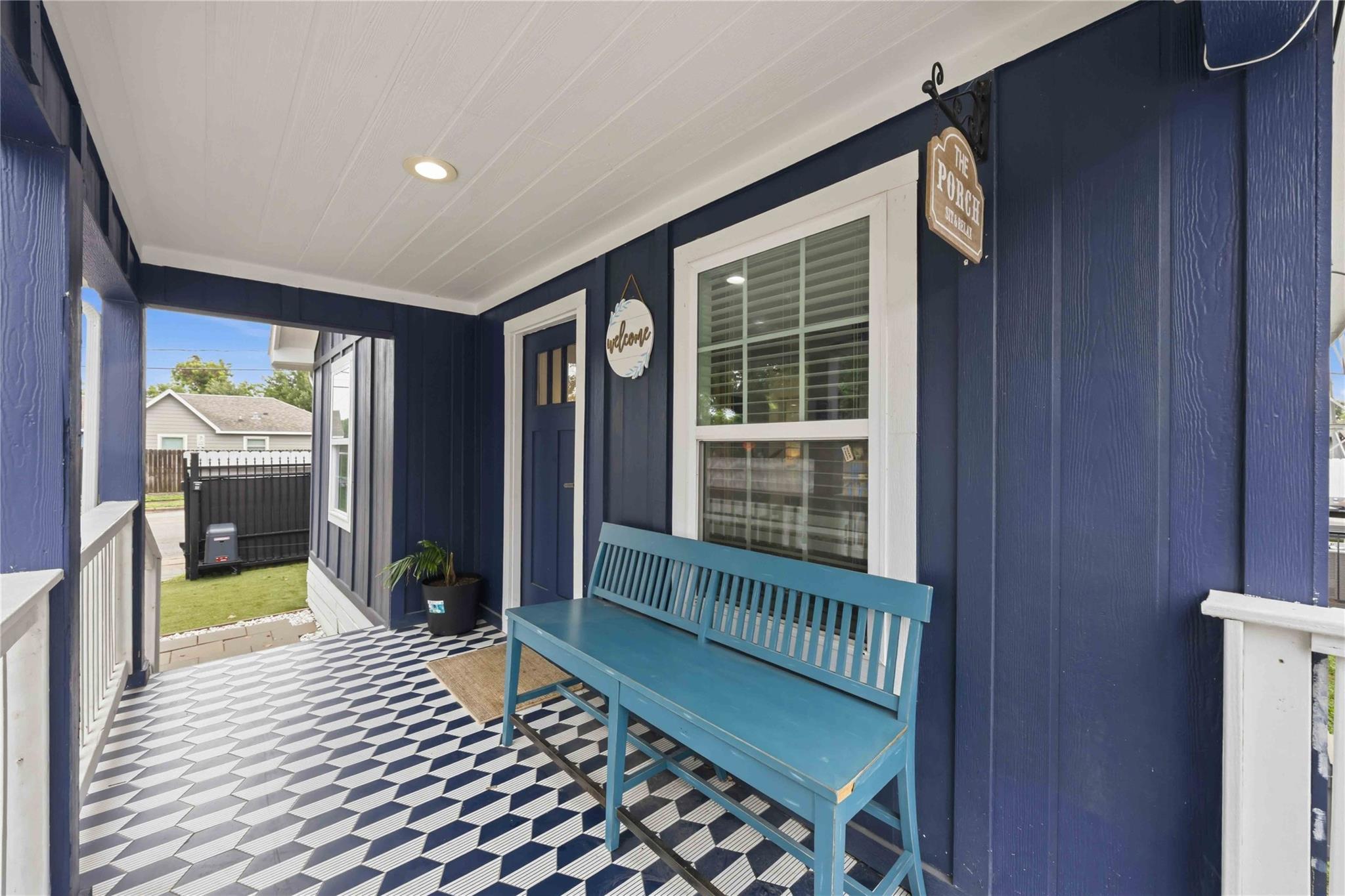 Covered navy porch with a turquoise bench and bold black-and-white patterned floor tiles.