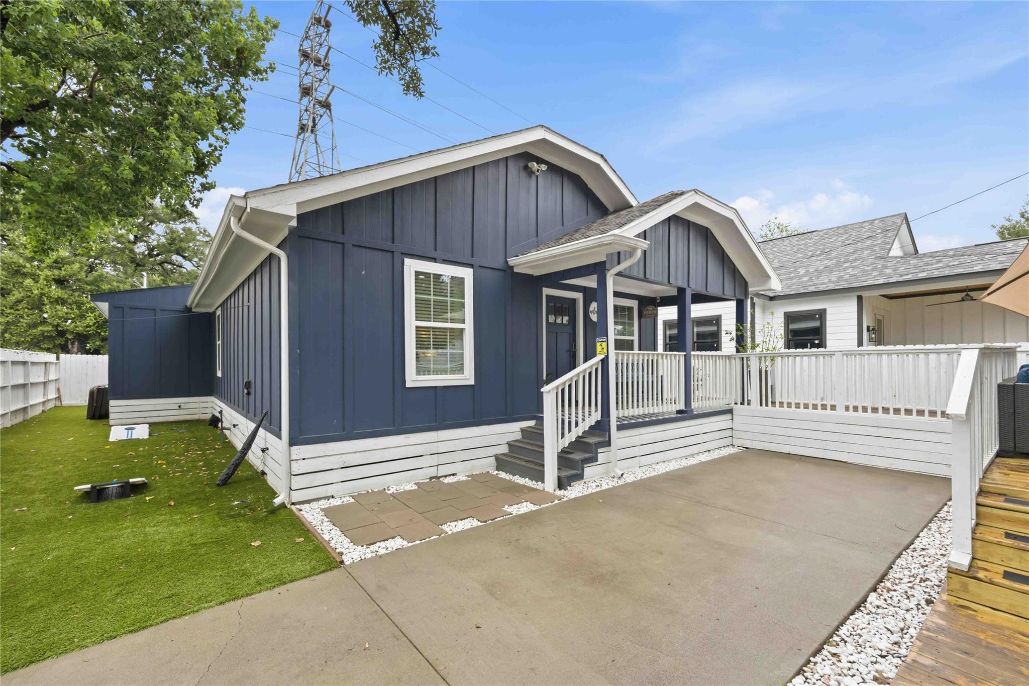 Navy-blue house with white trim, covered entry, and raised deck beside a concrete patio.