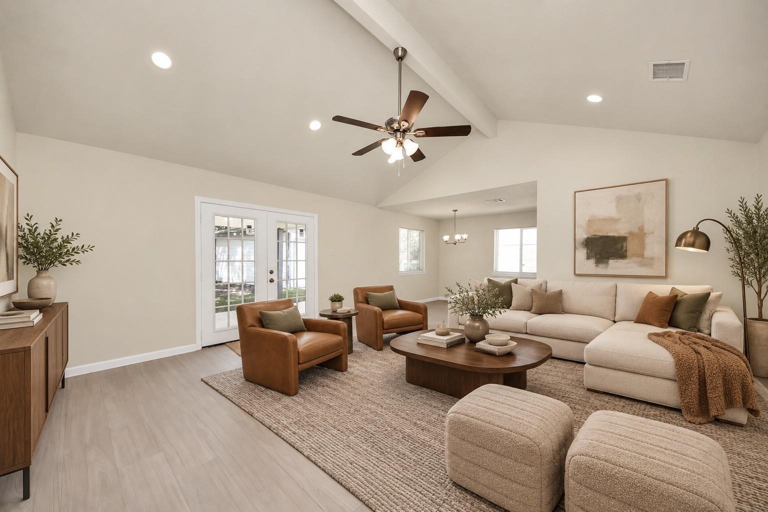 Living room with vaulted ceiling, cream sectional, leather armchairs, and French doors.