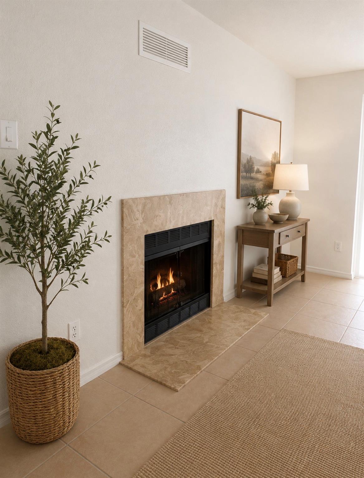 Living room fireplace with beige stone surround, potted tree, and wooden console table.
