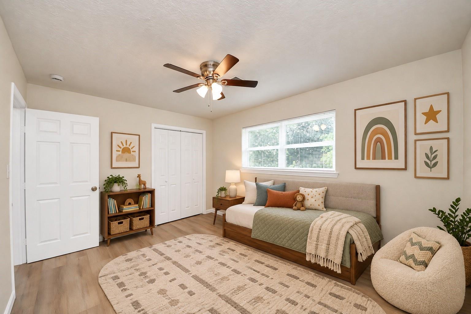 Staged bedroom with a wood-frame bed, colorful pillows, framed art, and a round upholstered chair.
