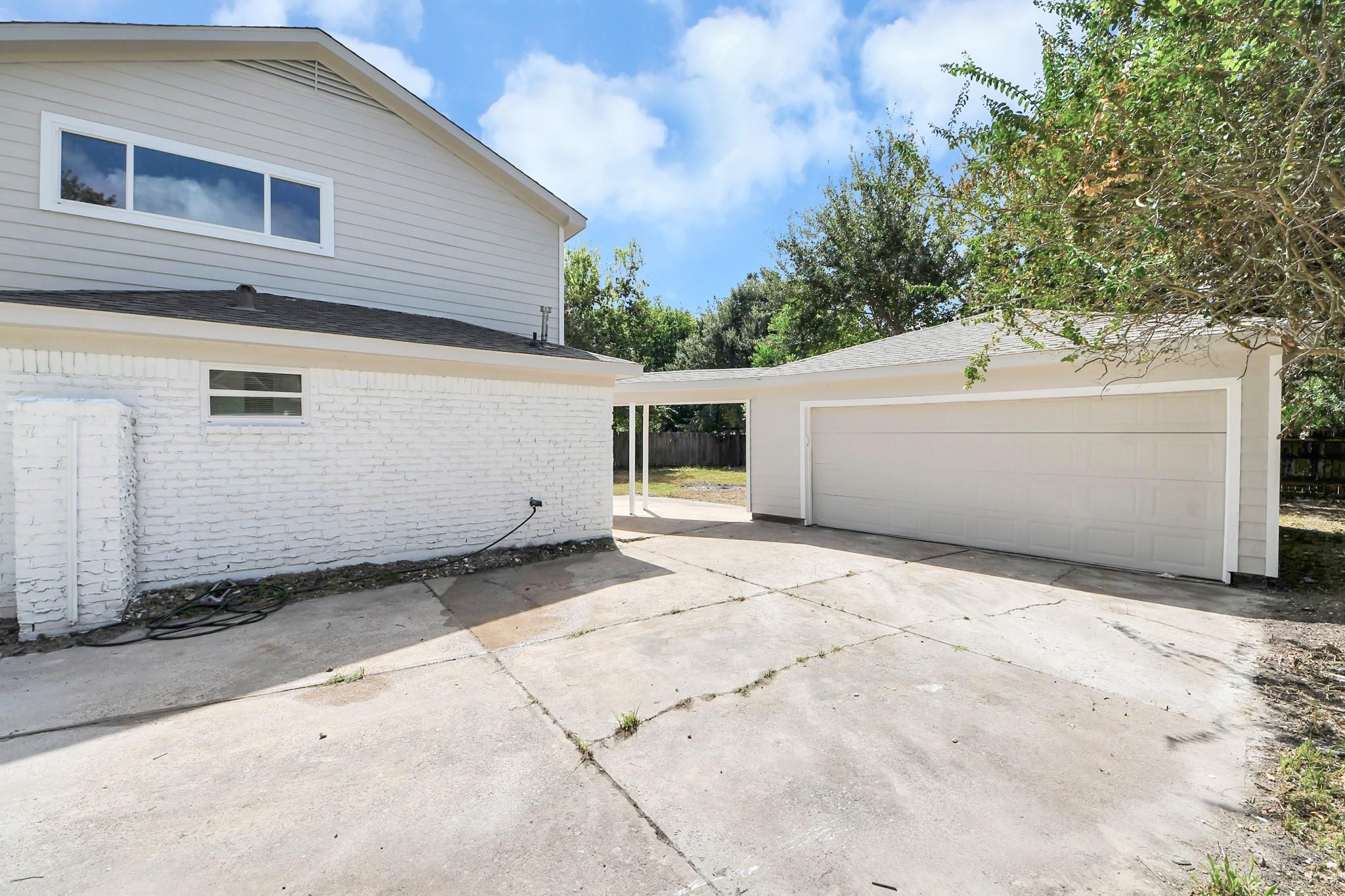 White two-story house with a broad concrete driveway and attached two-car garage.