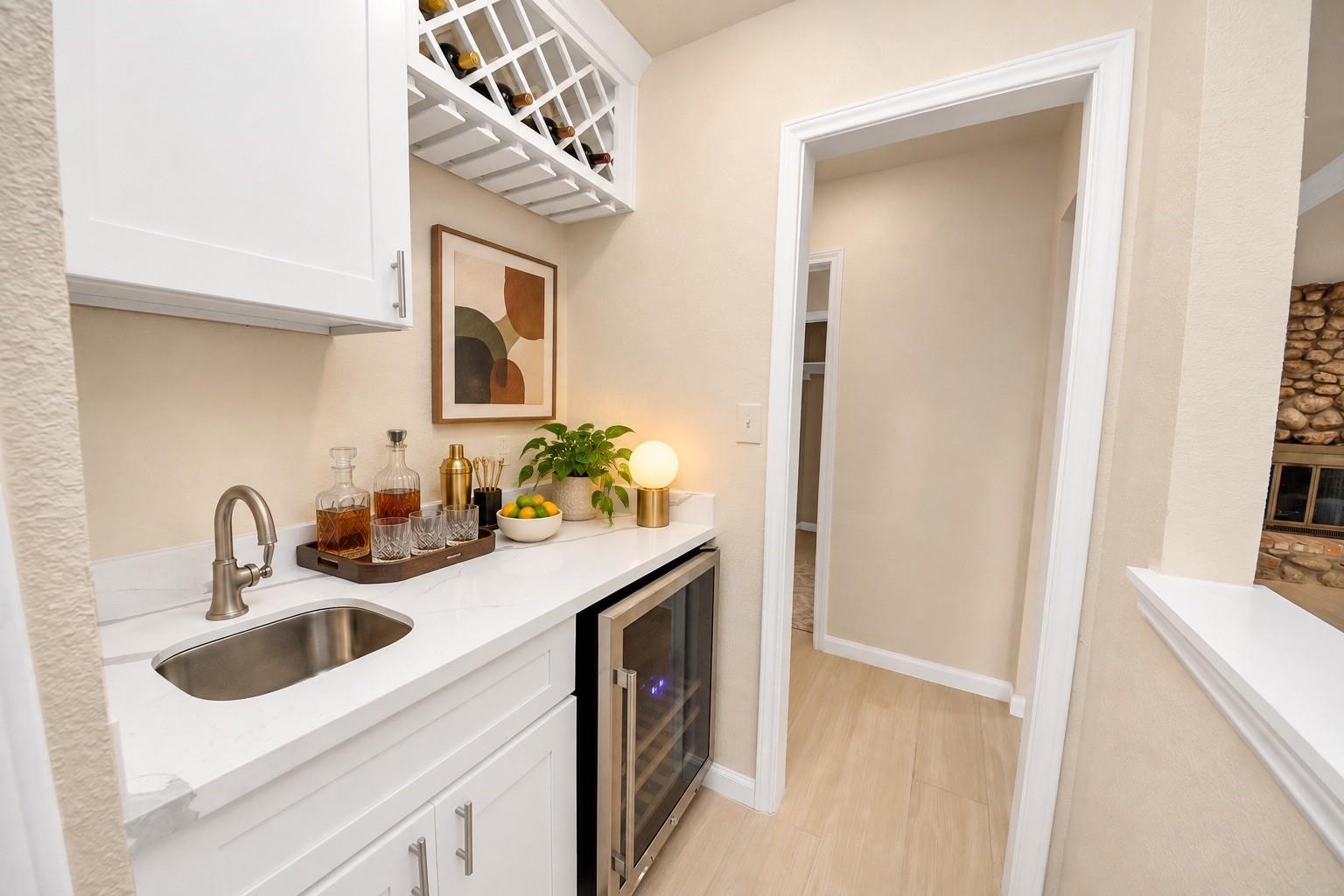 Home bar with a wine refrigerator, overhead wine rack, and white counter with sink.