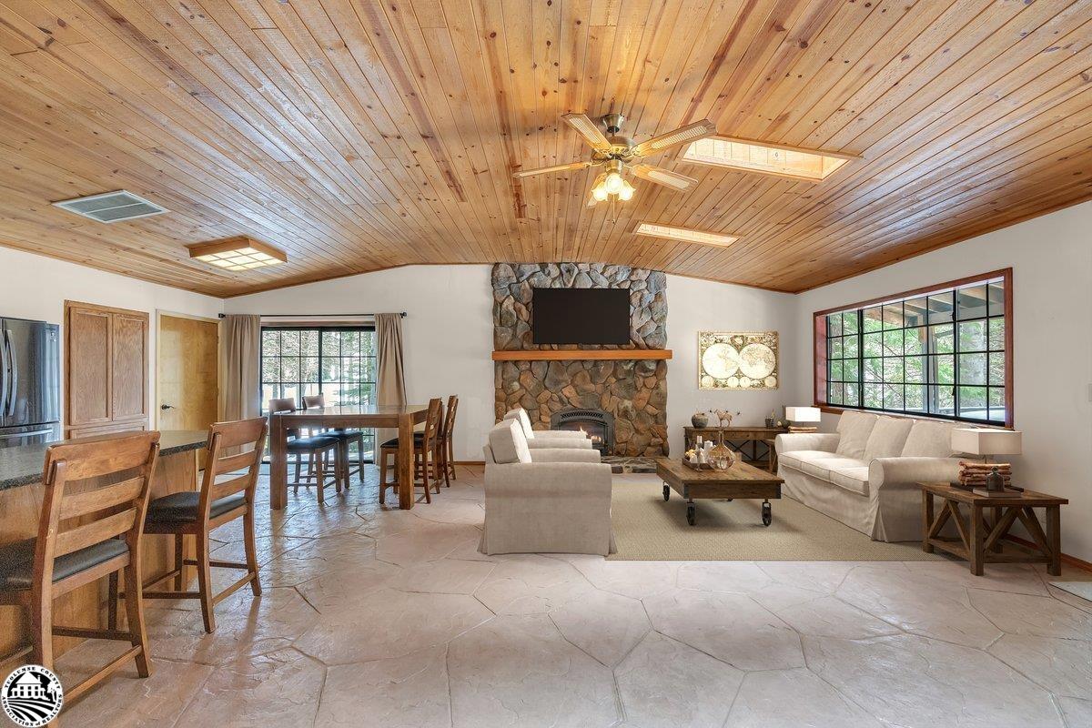 Living and dining room with a vaulted wood ceiling and stone fireplace.