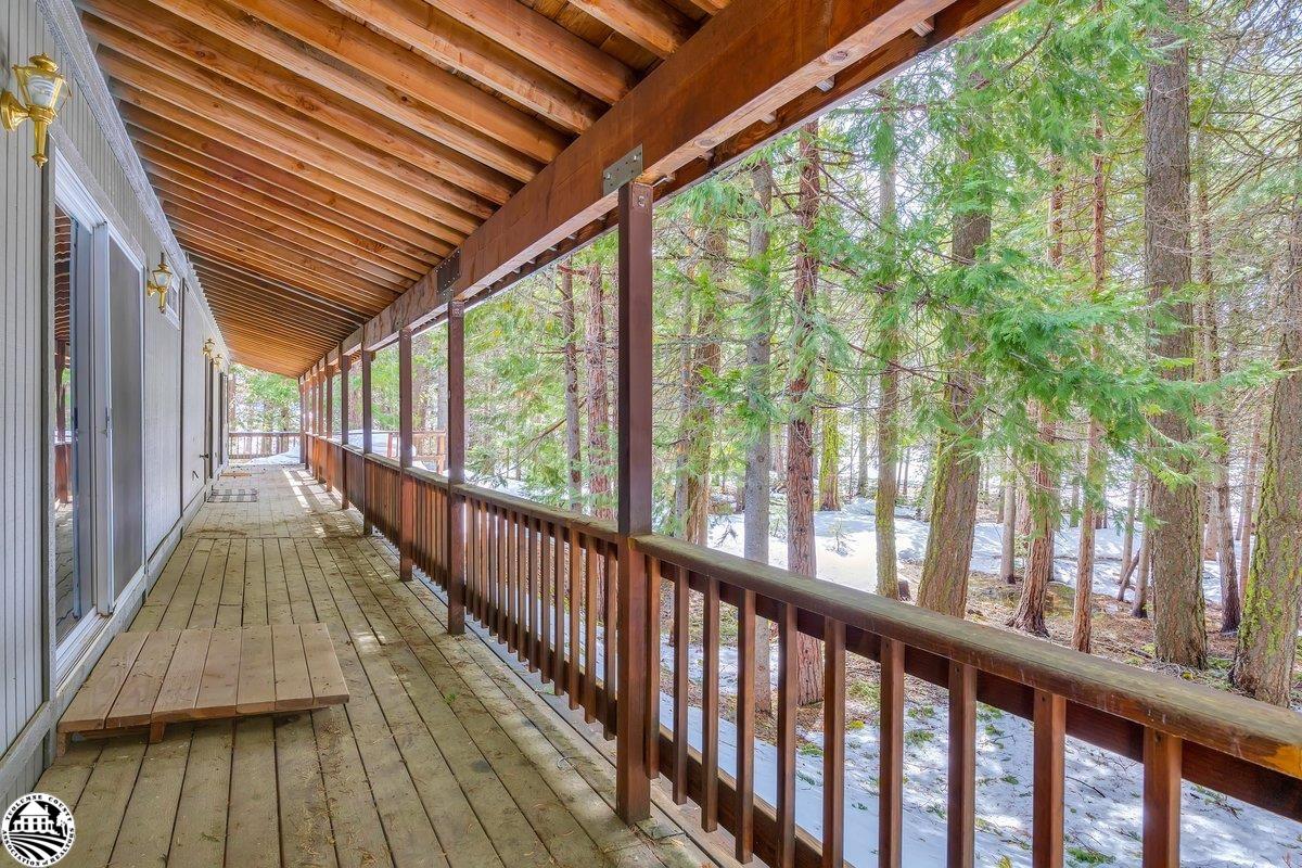 Covered wooden porch overlooking evergreen trees and patches of snow.