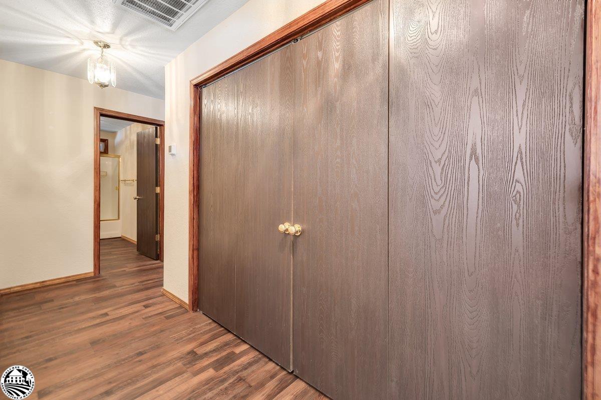 Hallway with dark wood closet doors and wood-look flooring, opening to a bathroom.