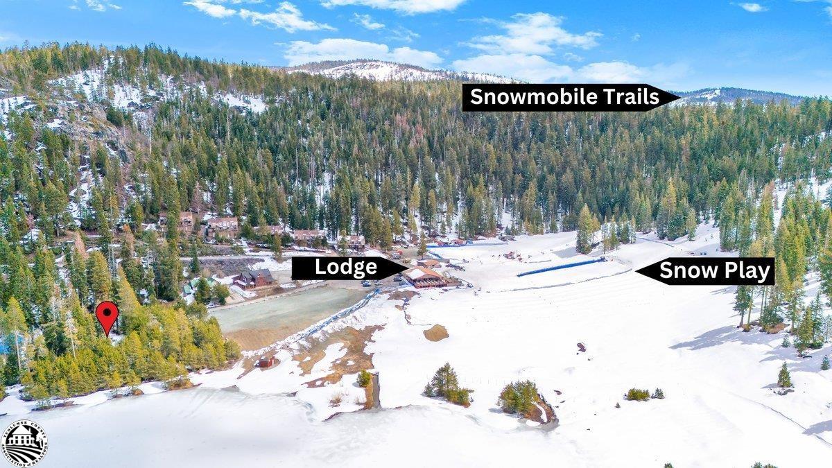 Aerial view of snowy Leland Meadows, with a lodge, forested slopes, snow play area, and snowmobile trails.