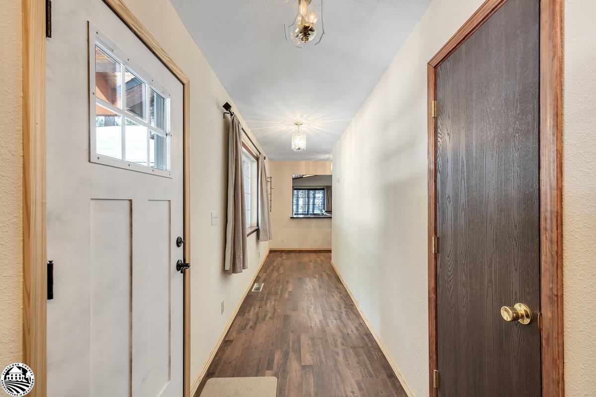Long entry hallway with wood-look floors, a windowed front door, side windows, and pendant lights.