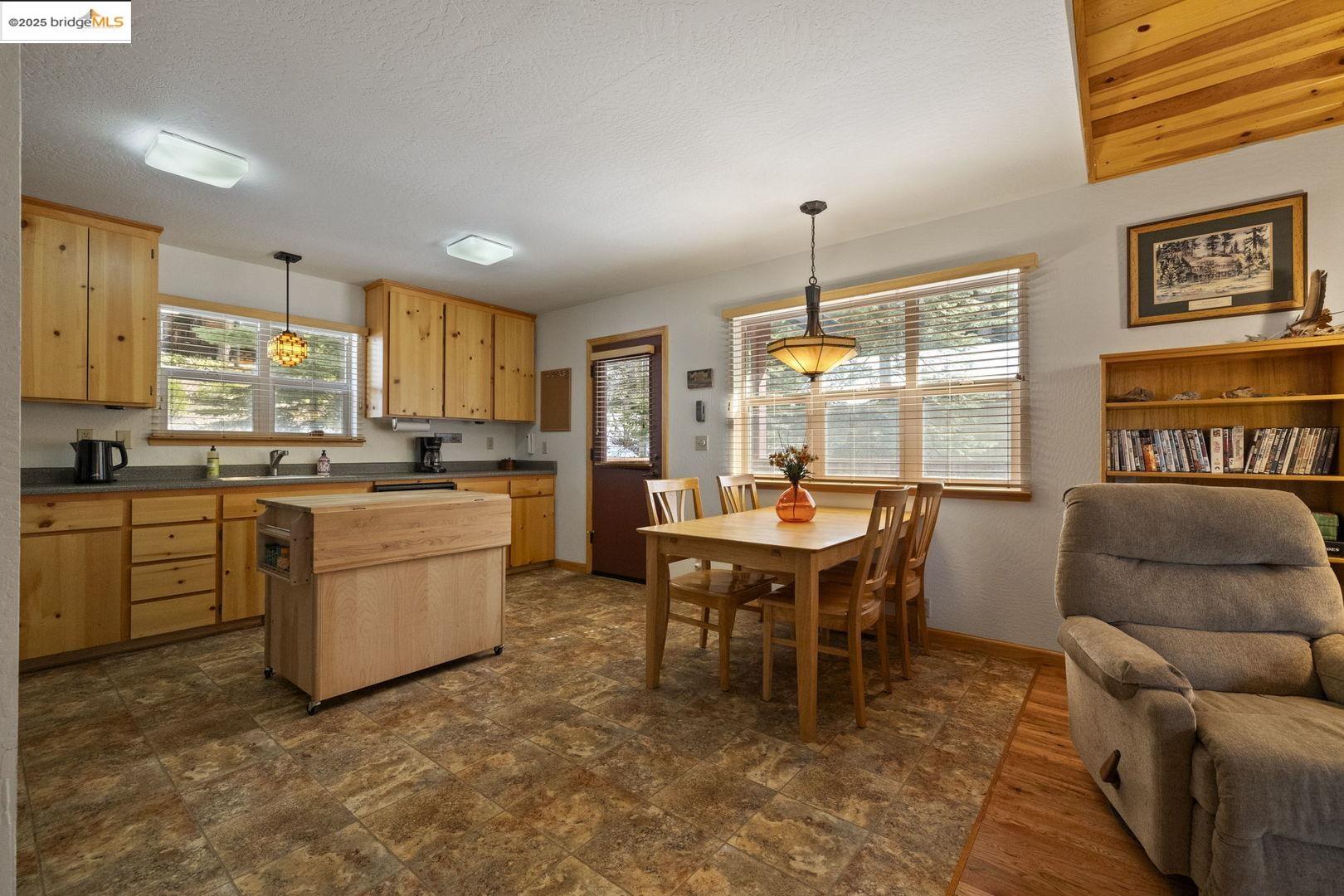 Kitchen and dining area with light wood cabinetry, a central island, and large windows.