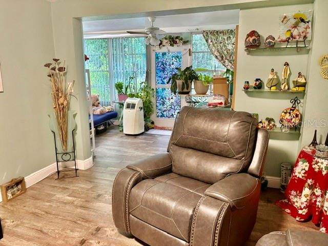 Living room with a brown leather recliner and an adjoining plant-filled sunroom.