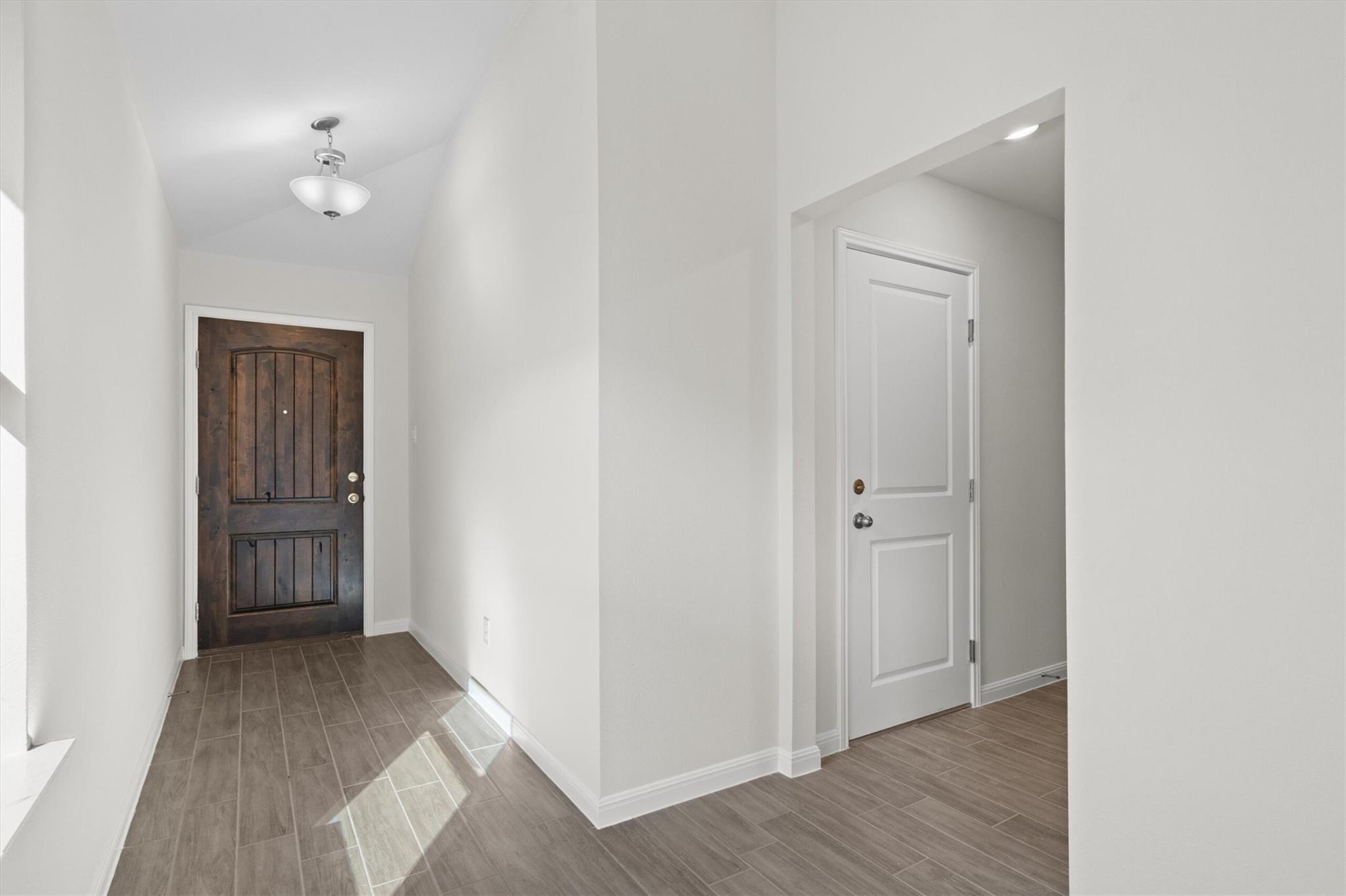 Entry foyer with gray tile floors, a dark wood front door, and a white interior door.