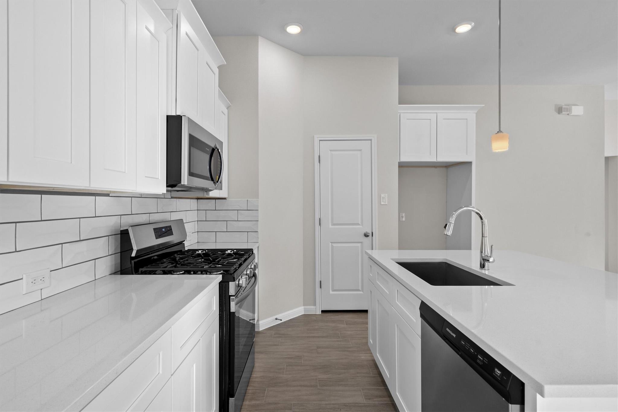 Modern white kitchen with subway tile, gas range, and island sink with chrome faucet.