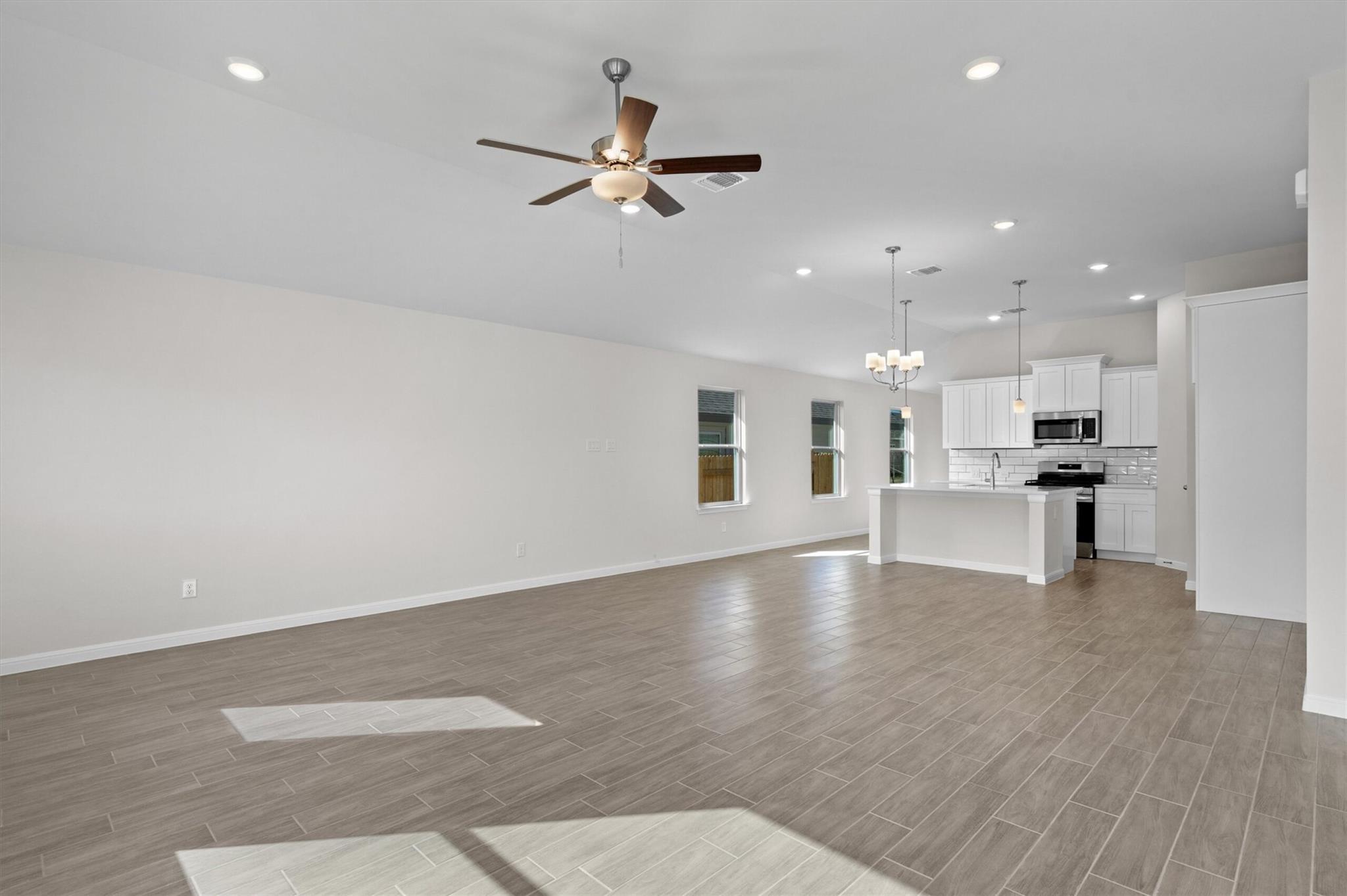 Vacant open-plan kitchen and living area with a large island and gray tile flooring.