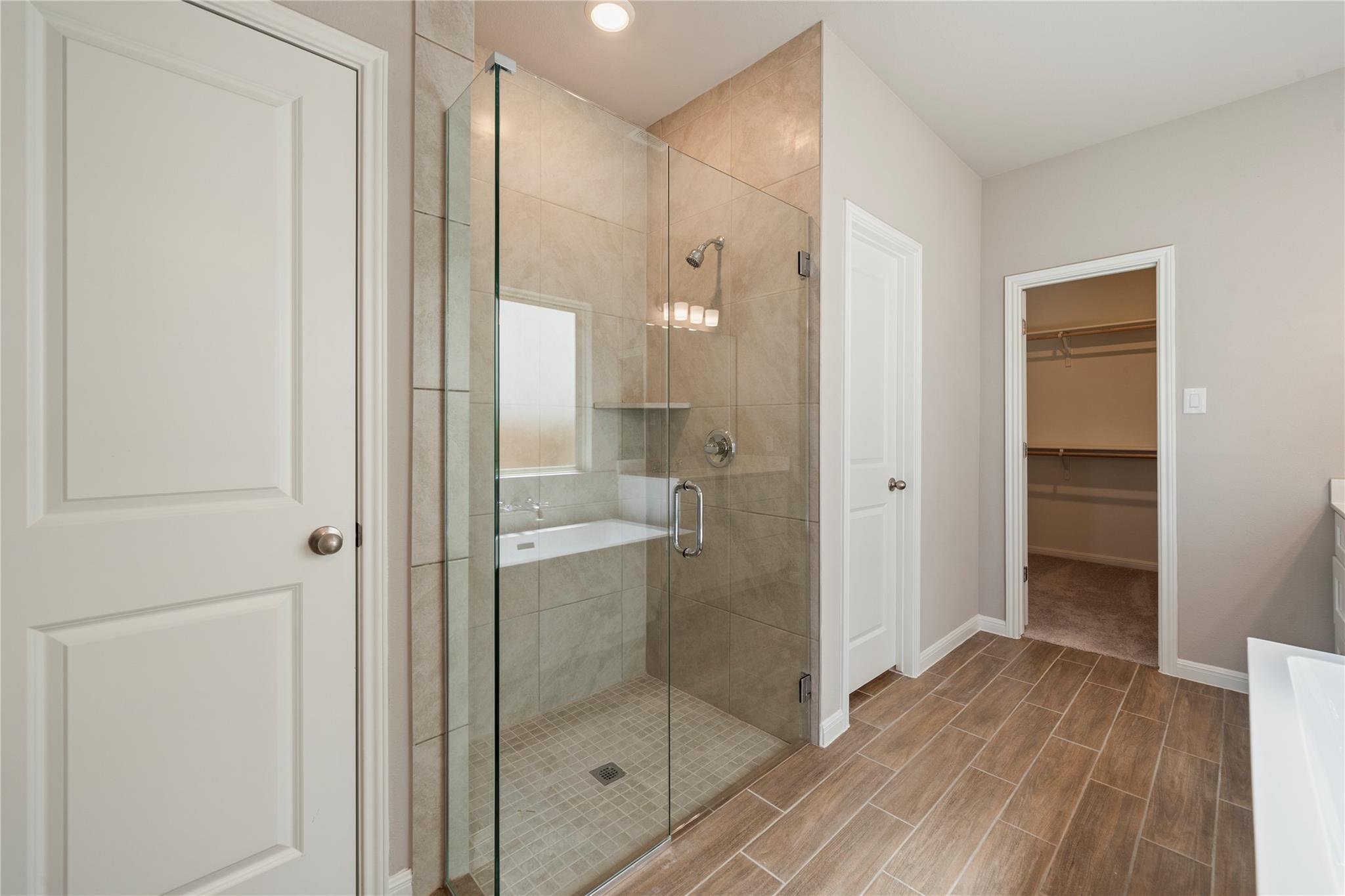 Bathroom with a glass-enclosed tiled shower and an open doorway to a walk-in closet.