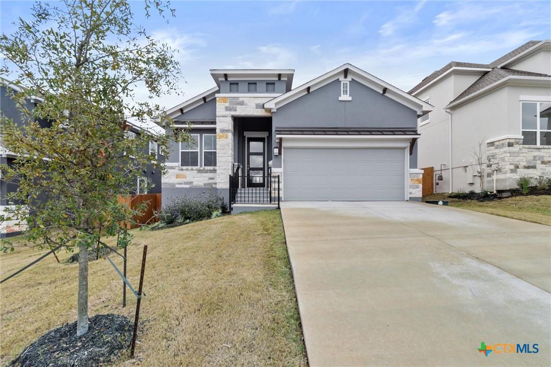 Gray and stone home with a covered entry, two-car garage, and wide driveway.