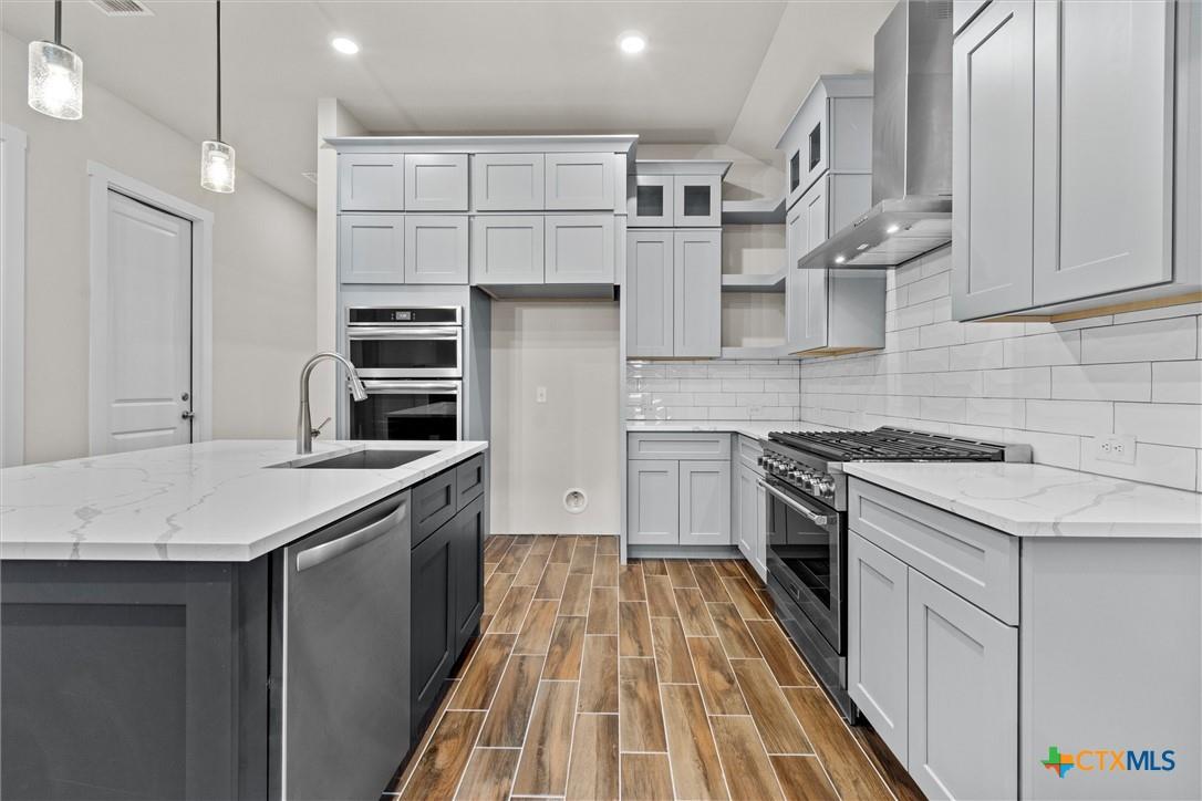 Modern kitchen with a veined-stone island, gray cabinets, stainless appliances, and wood-look flooring.