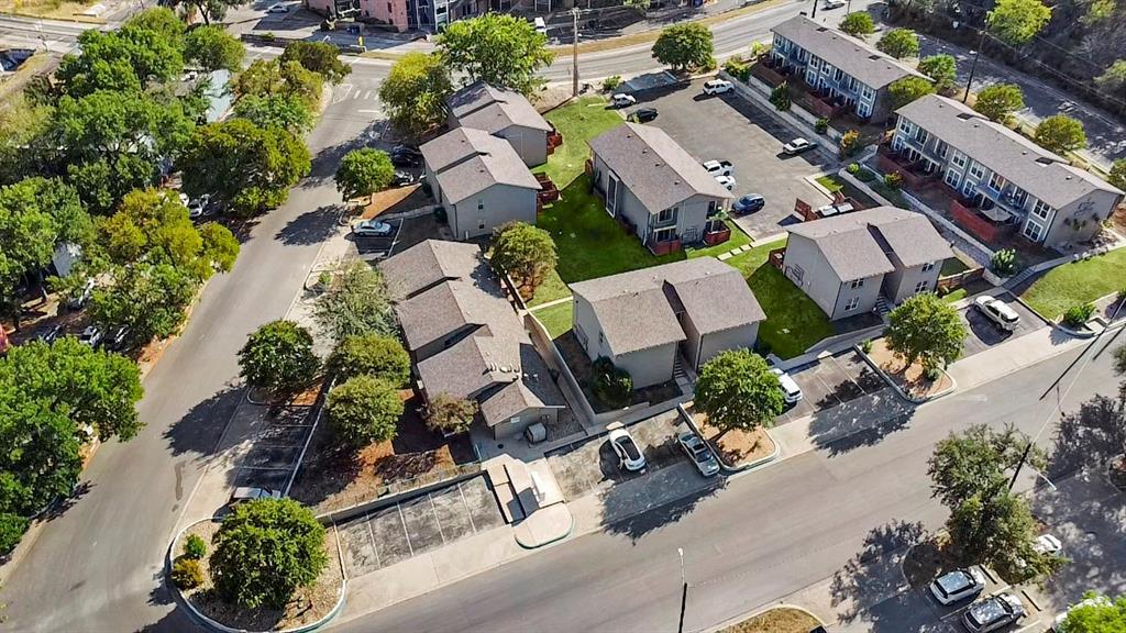Aerial view of a condominium complex with low-rise buildings, parking areas, and mature trees.