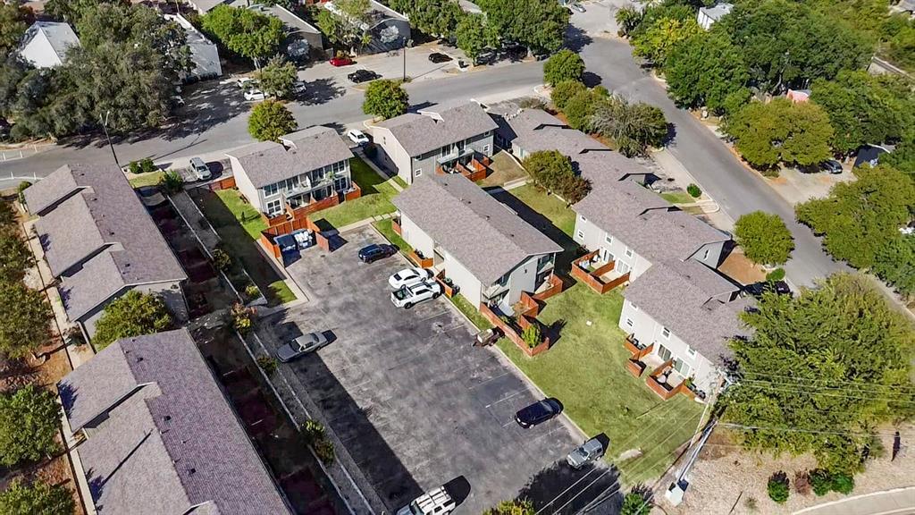 Aerial view of condominium buildings with fenced patios and a central parking lot.