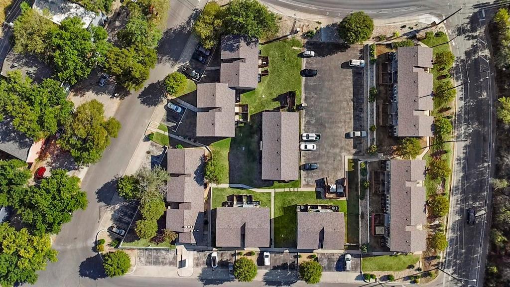 Aerial view of a residential complex with multiple buildings, central parking, and mature trees.