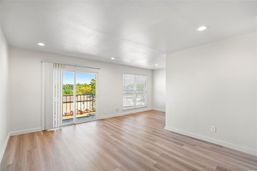 Vacant living room with light wood-look floors and a sliding glass door opening to a balcony.