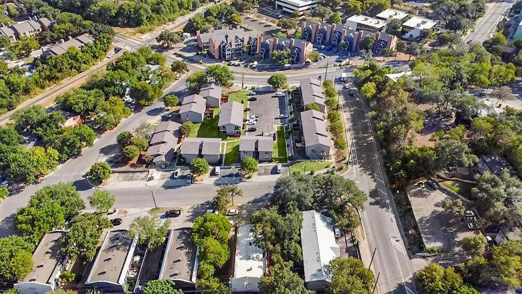 Aerial view of a low-rise residential community surrounded by mature trees and streets.