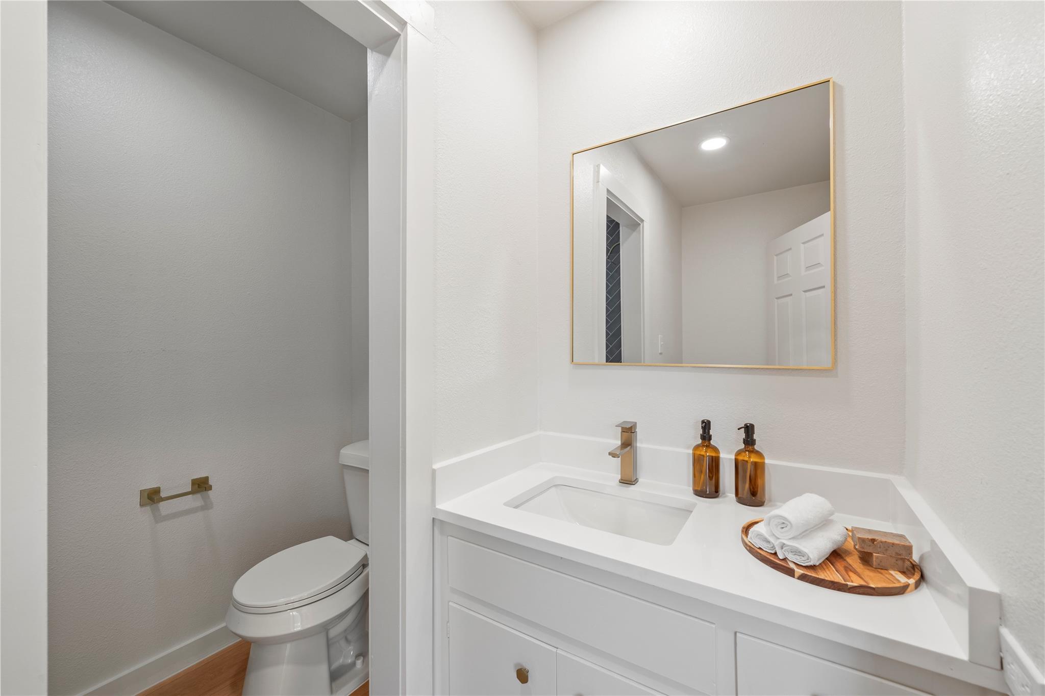 Bathroom with a white vanity, gold-tone fixtures, and a toilet beside the sink.