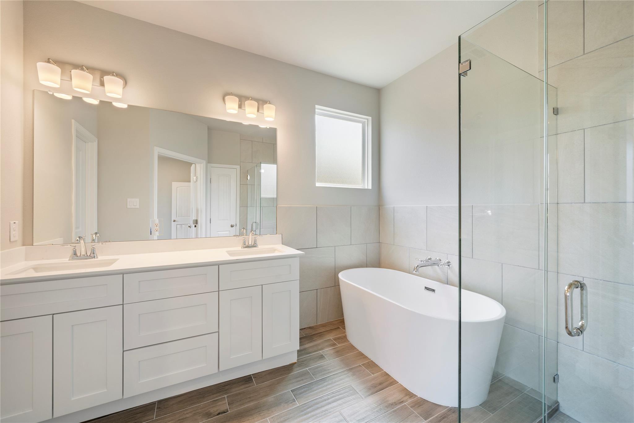 Bathroom with a double-sink vanity, freestanding soaking tub, and glass-enclosed shower.