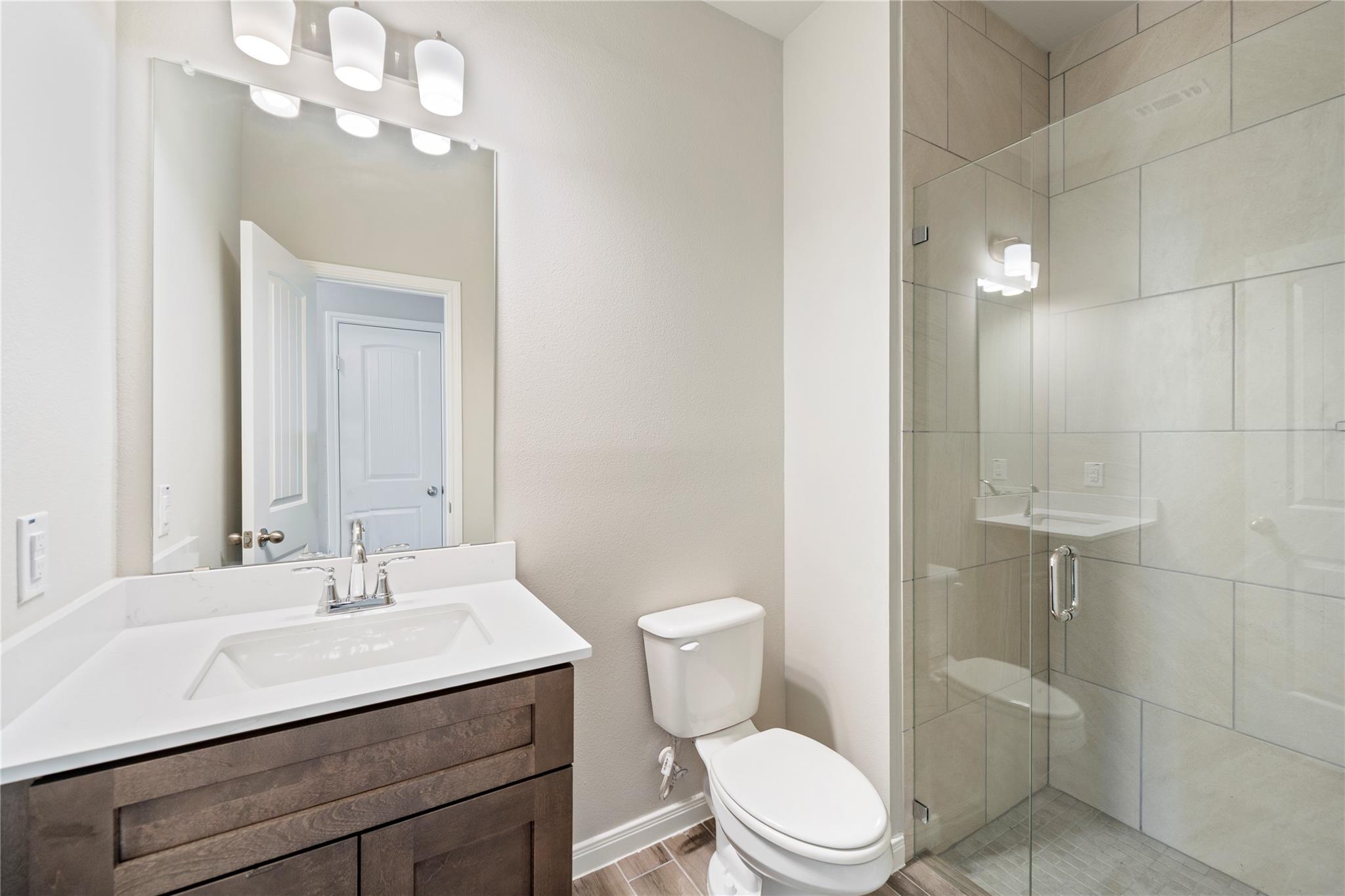 Bathroom with a dark wood vanity and a glass-enclosed, tiled walk-in shower.