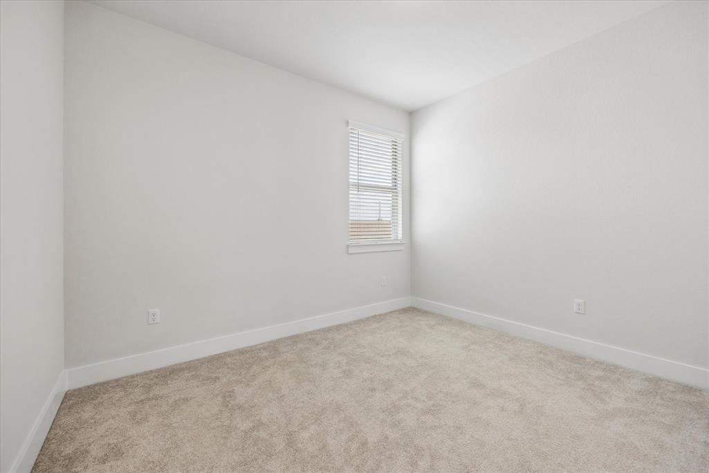 Empty carpeted room with white walls and a window with blinds.