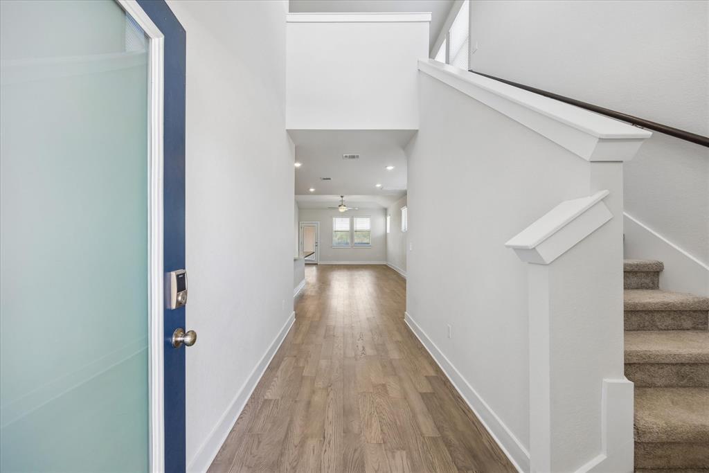 Entry hallway with wood-look flooring, a glass front door, and carpeted stairs.