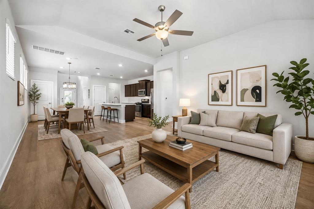 Open-plan living room with a light sofa, wood coffee table, and dining area beside the kitchen.