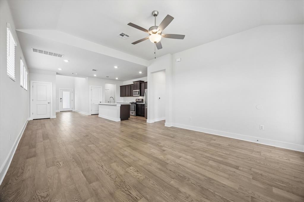 Open living area with wood-look floors, a high ceiling, ceiling fan, and kitchen peninsula.