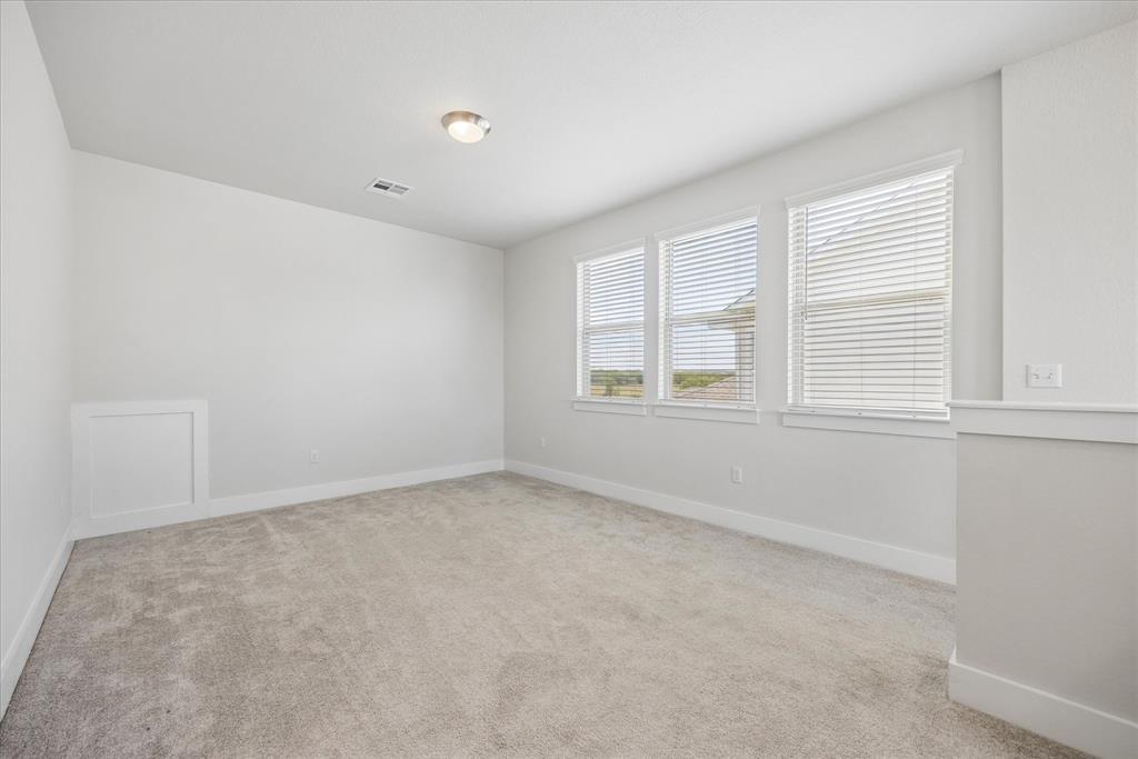 Empty carpeted room with three windows fitted with white blinds.