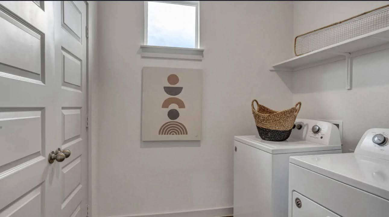 Laundry room with white washer and dryer, open shelves, and geometric wall art.