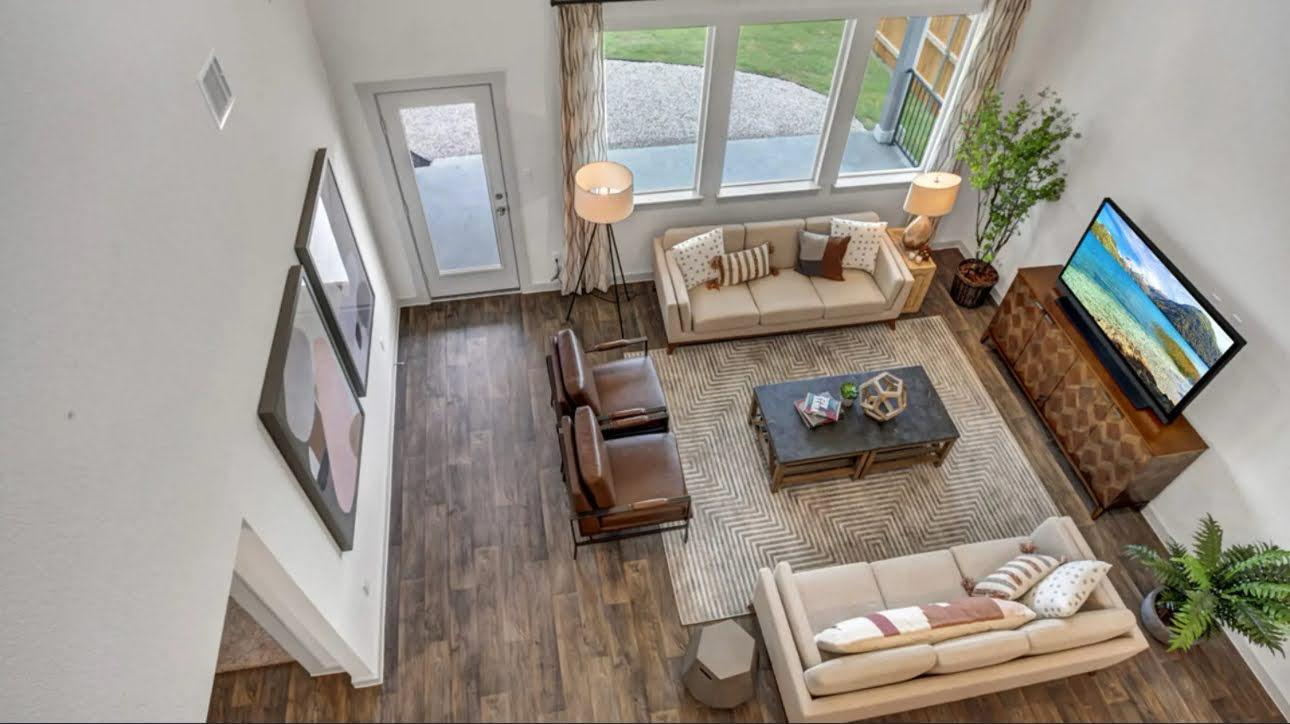 Staged living room with two cream sofas, leather armchairs, and tall windows.