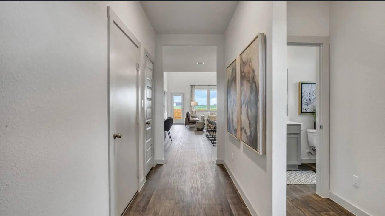 Bright hallway with wood-look flooring and framed artwork, opening toward the living area.