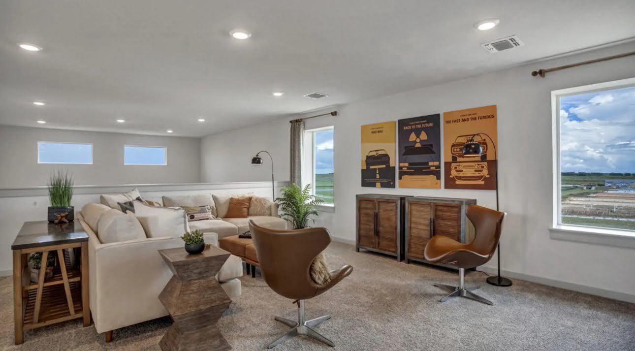Living room with a cream sectional, brown swivel chairs, movie posters, and large windows.