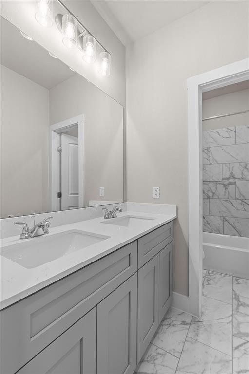 Bathroom with a double-sink vanity, large mirror, and marble-patterned tub surround and floor.