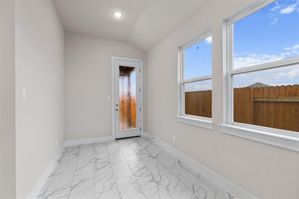 Bright tiled room with large windows and a frosted-glass exterior door overlooking a fenced yard.