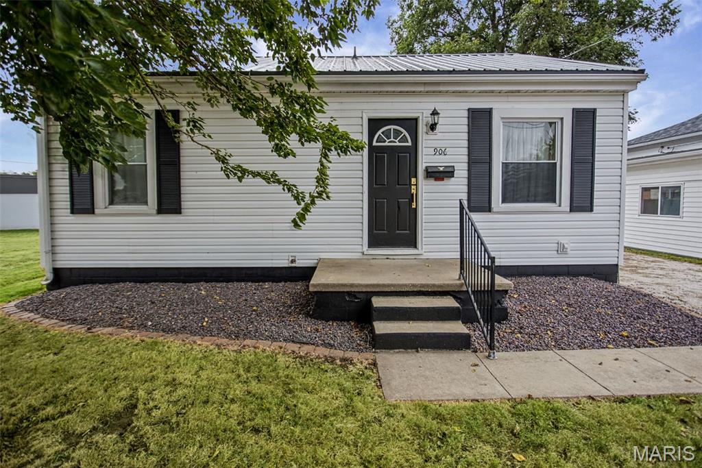 Single-story white house with black shutters, a dark front door, and gravel landscaping.
