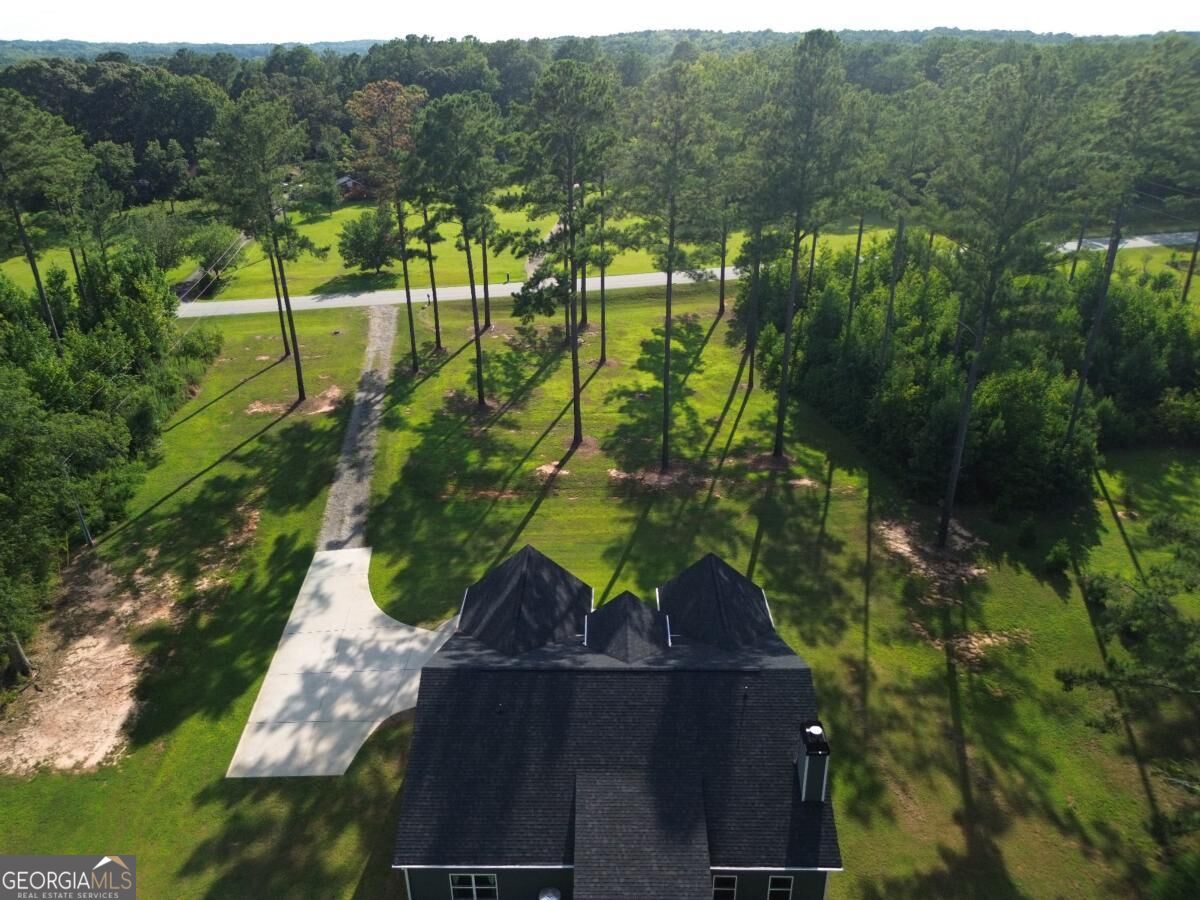 Aerial view of a wooded property with a long driveway leading to a house.