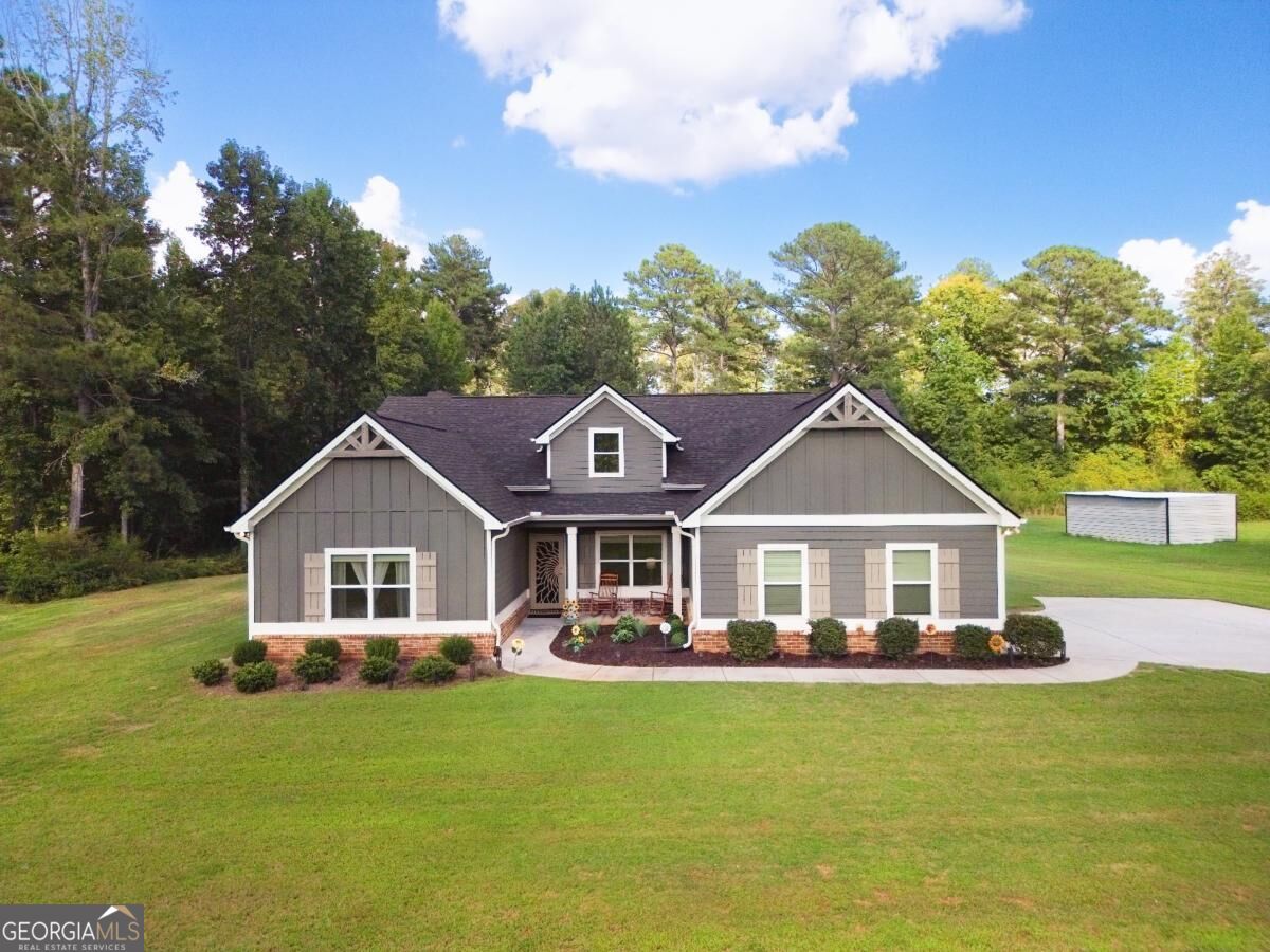 Gray single-story home with white-trimmed gables, landscaped front beds, and a broad lawn.
