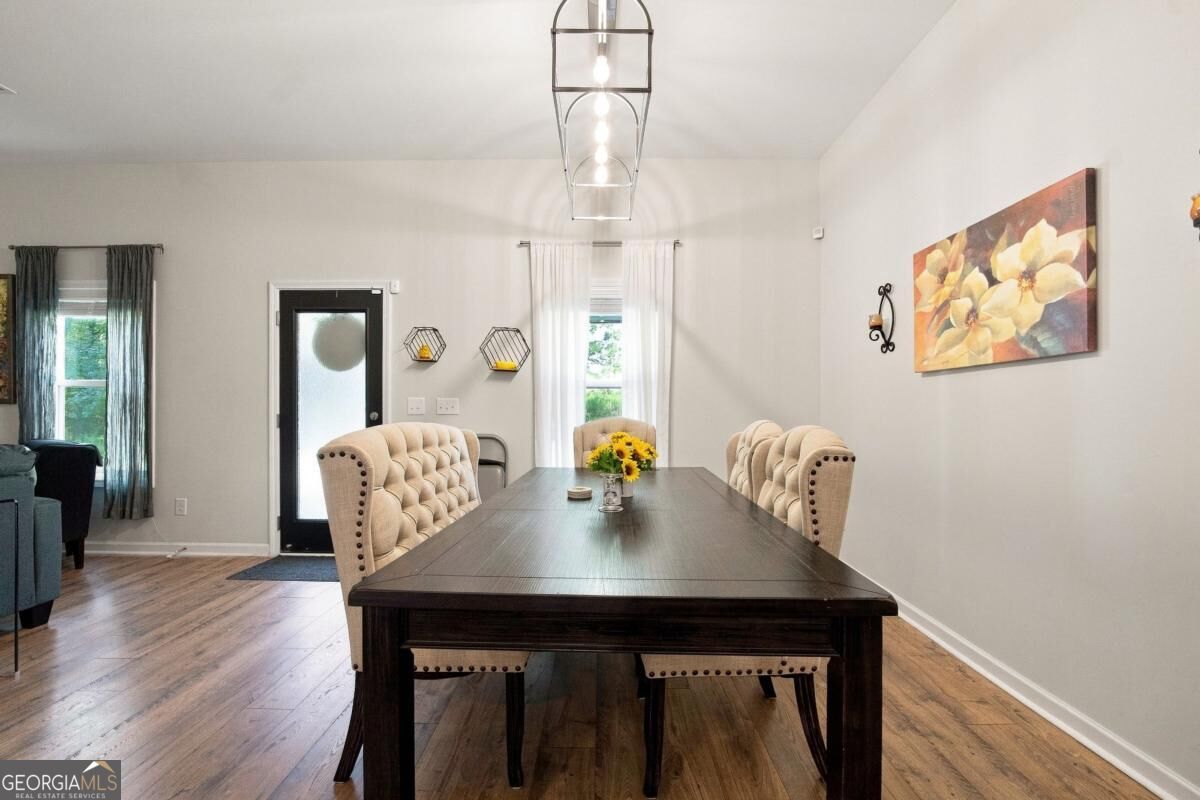 Dining room with a long dark wood table, tufted beige chairs, and a geometric pendant light.