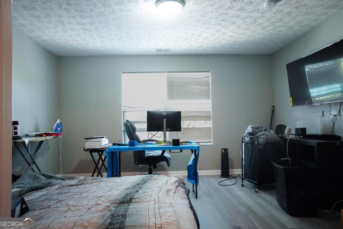 Bedroom with a bed, desk by the window, and wall-mounted television.