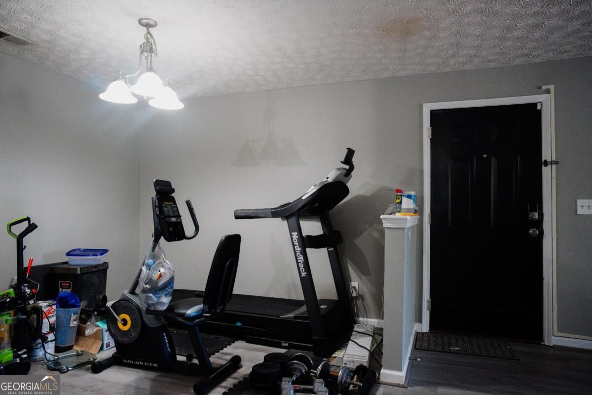 Home gym with a treadmill, stationary bike, and weights beside a black door.
