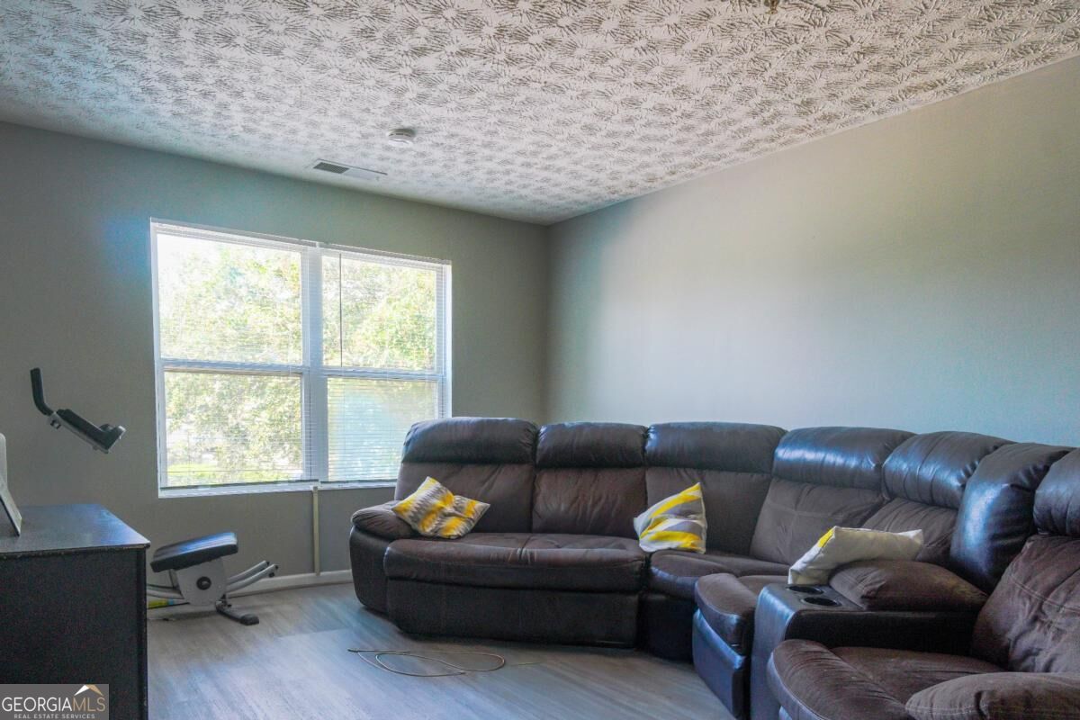 Living room with a dark leather sectional, bright window, and compact exercise machine.